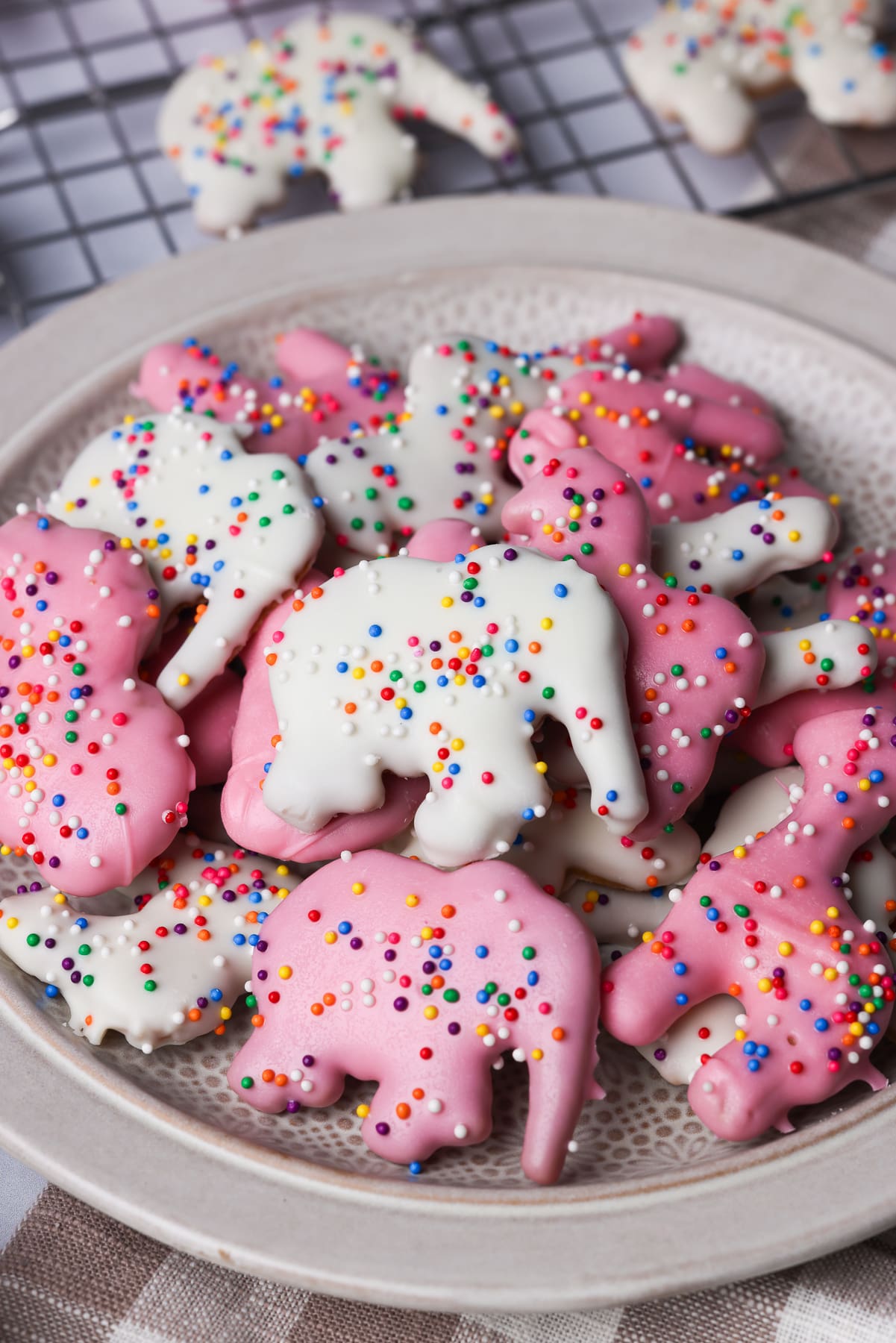 homemade pink and white circus animal cookies on a plate. They are topped with colorful sprinkles.