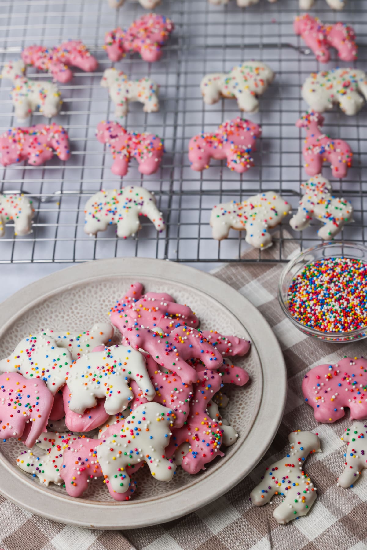 homemade circus animal cookies on a table. there are a couple on a plate and some on a cooling tray.