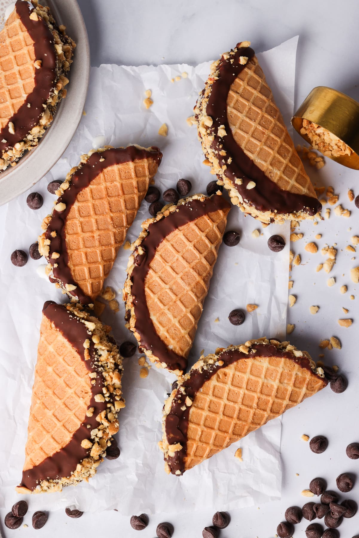 waffle cone taco shells that are filled with ice cream. They were dipped in chocolate. there are chopped nuts.